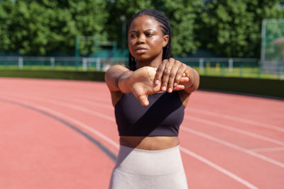 African american female stretches hands warming up before intensive workout on sunny summer day