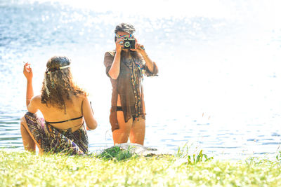 Woman photographing standing by lakeshore