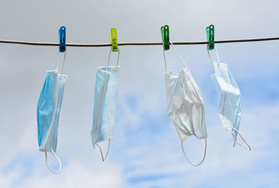 Low angle view of clothespins hanging on clothesline against sky