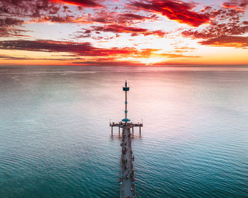 High angle view of people on pier over sea against orange sky