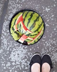 Low section of person standing next to melon