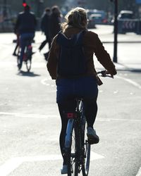 Rear view of woman riding bicycle on road