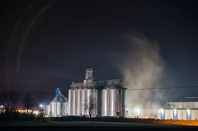 Grain dryer plant working at night with steam floating around it. modern farm. poland