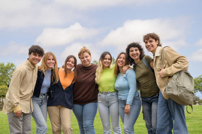 Portrait of smiling friends standing against sky