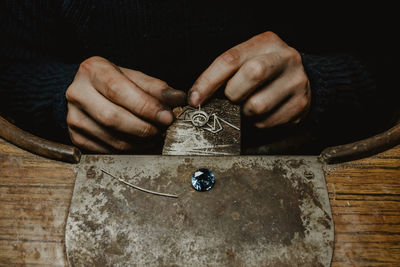 Jeweler holding unfinished ring in dirty hands and checking quality in workshop