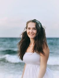 Portrait of young woman standing at beach