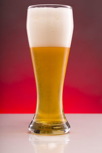 Close-up of beer glass against red background