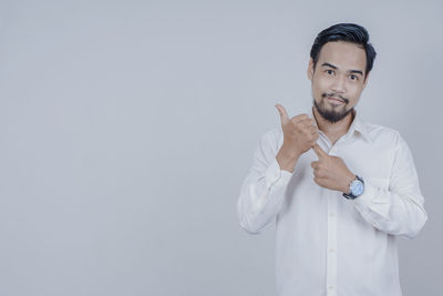 Portrait of young man standing against white background