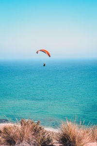 Scenic view of sea against sky with paraglider 