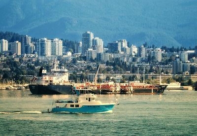 Sailboats in sea against buildings in city