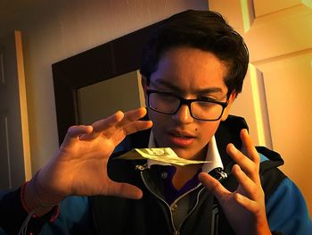 Close-up of teenage boy levitating paper currency at home