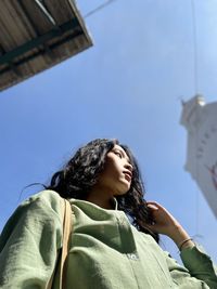 Low angle view of young woman against sky