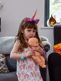 Cute girl holding toy while sitting at home