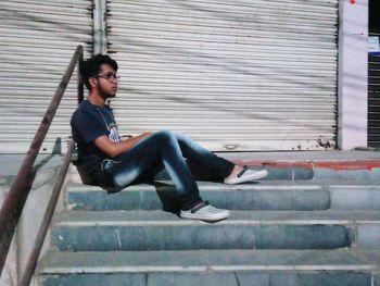 Side view of young man sitting on staircase