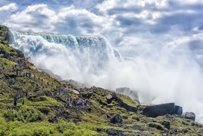 Scenic view of waterfall against cloudy sky