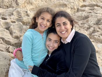 Portrait of mother with two young girls daughters sitting near the beach sea