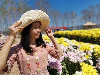 Young woman with arms outstretched standing against plants