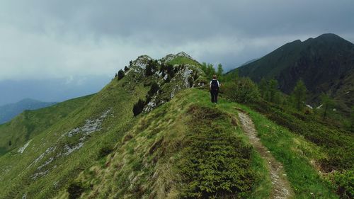 Rear view of man walking on mountain against sky