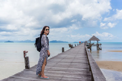 Woman standing on pier over sea against sky