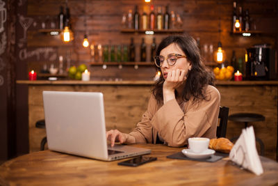 Young woman using mobile phone at table