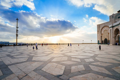 People at mosque hassan ii against sky in city