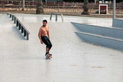 Man riding skateboard in urban street skatepark. casual guy wearing shorts and bare chest.