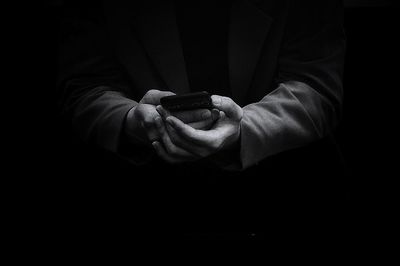 Midsection of man holding smart phone against black background