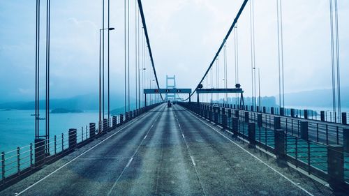 Suspension bridge over sea against sky