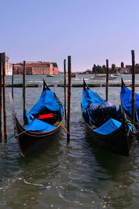 Boats moored in canal against clear sky