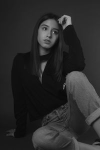Portrait of young woman against black background
