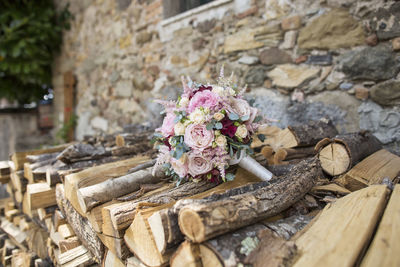 Detail of the bride's bouquet composed of roses and peonies laid on stacked wood
