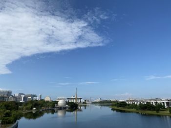 Scenic view of river by buildings against blue sky
