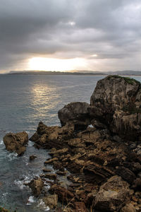 Rock formation on sea against sky during sunset