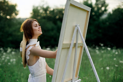 Portrait of young woman standing against trees