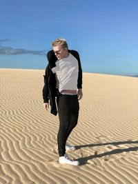 Man standing on sand dunes at desert against clear sky