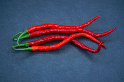 High angle view of red chili peppers on blue background