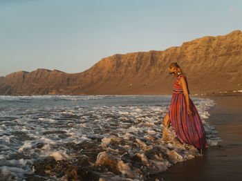 Side view of woman walking on shore at beach