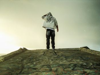 Rear view of man standing on footpath against sky