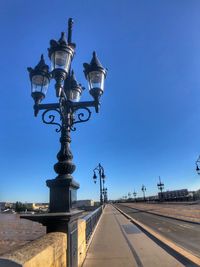 Street lights on bridge over river against clear blue sky