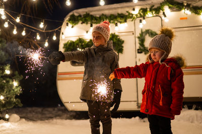 Cute kids playing with sparkler against van