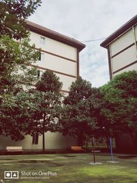 Trees by building against sky