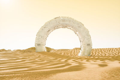 Arch on beach against clear sky