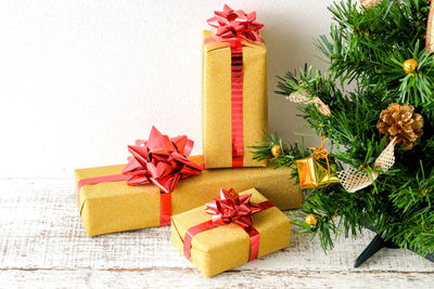 Close-up of christmas tree and presents against wall