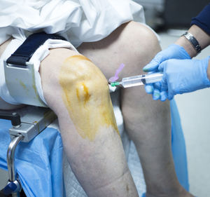 Cropped hands of doctor injecting knee