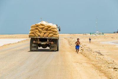 Boy running on road by cargo truck