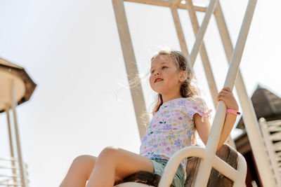 A charming girl is having fun on a swing on a summer day. childhood, recreation, summer time