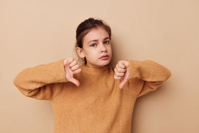 Portrait of young woman standing against pink background