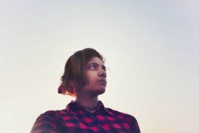 Beautiful young woman against clear sky over white background