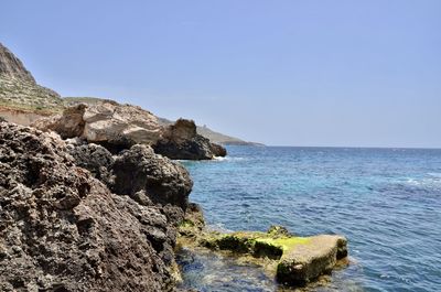 Scenic view of rocks in sea against clear sky