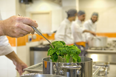 Cropped hand of chef preparing vegetable in restaurant